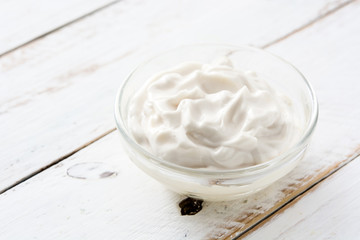 Sour cream in crystal bowl on white wood. Copyspace