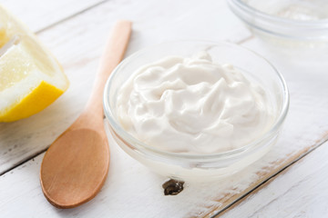 Sour cream in crystal bowl on white wood. 