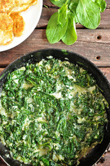 Spinach in a cream sauce in a pan on a wooden background