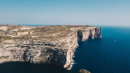 Beautiful aerial view of dramatic high precipice with beautiful sea view. Yacht sailing boat in the sea. Drone top view shot of dangerous stony cliffs. Gozo island, Malta