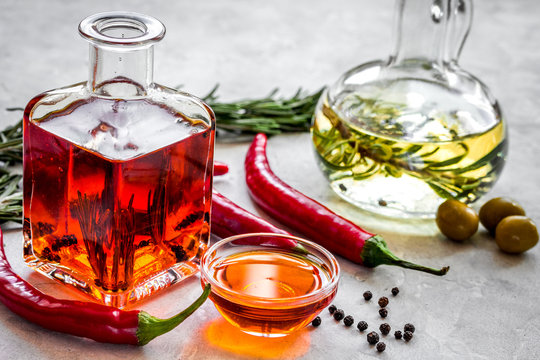 oil in carafe with spices, olives and chili on stone background