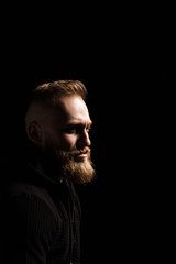 male portrait of a guy with a beard on a black background close-up