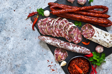 Plate with delicacies. Hamon, salami, meat with nuts and spices on a concrete background.