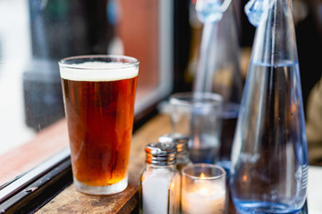 IPA beer next to a window at a rustic bar next to bottles and glasses of water