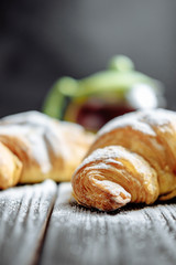 croissants with tea on dark wooden background close-up
