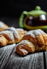 croissants with tea on dark wooden background close-up