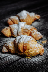 three croissants on dark wooden background close-up top view