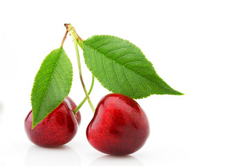 Ripe cherries with green leaves close-up, isolated on white background.