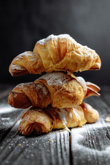 three croissants on dark wooden background close-up