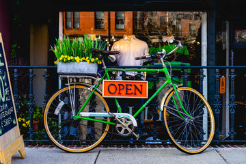 Vintage green bike with an open sign in front of a store