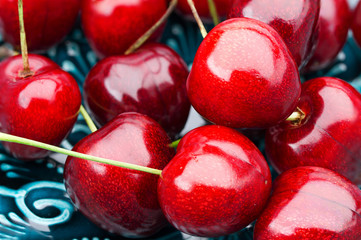 Ripe cherries close-up, on a blue plate.