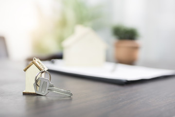 house key on table with contract form, selling and buying home or condo concept