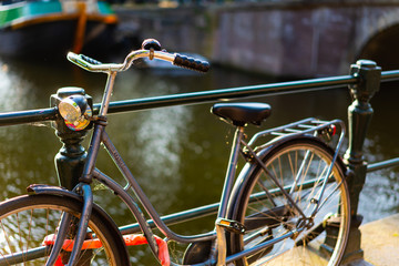 Fototapeta na wymiar Bike against a rail over a canal in golden hour