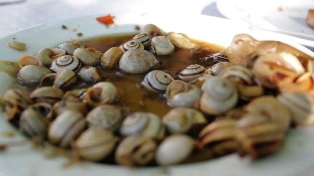 Eating cooked snails or escargot from plate