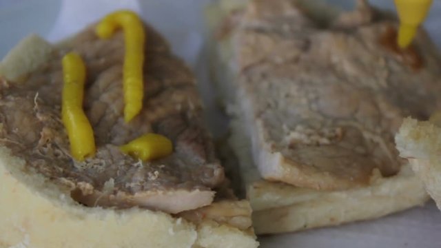 Putting mustard on a Traditional portuguese pork beef sandwich bifana