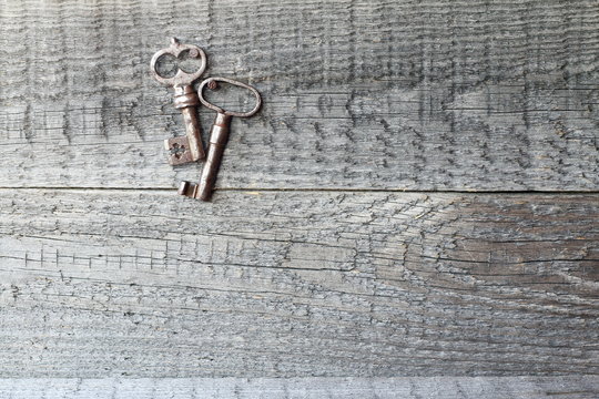 A pair of old keys on a wooden background.