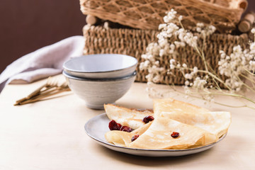 Homemade gluten free rice crepes or pancakes served with dried cranberries on wooden table. Healthy breakfast