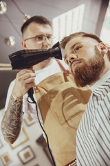 Male hairdresser dries hair of his client. Photo in vintage style