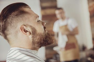 Fototapeta premium Close-up of man's face with a beard while he is waiting for a barber. Photo in vintage style