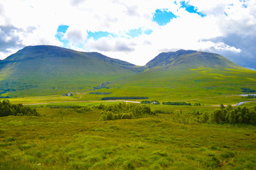 View of Scottish Highlands, in Scotland. Beautiful green grass field in middle of mountains