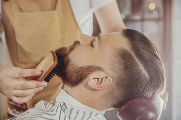 Crédence de cuisine en verre imprimé Salon de coiffure Le barbier peigne la barbe de l& 39 homme avec une brosse. Photo dans un style vintage