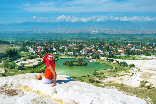 Tourist woman sitting on white pamukkale terrace and pictures on the phone.Travel concept.