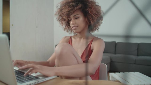 Young Afro American woman using laptop computer while sitting at table.