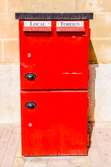 Red letterbox with slots for local and foreign mail.