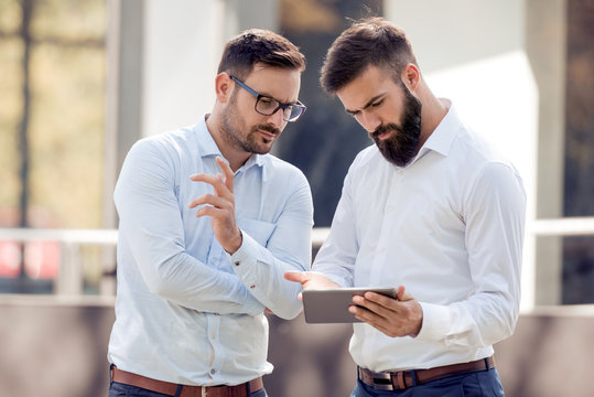 Two Business People Outside Looking At A Tablet