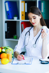 Health. Diet and Healthy. Nutrition. Portrait of a Dietitian's Doctor with Fresh Fruits and Vegetables. Beautiful and Young Doctor in the Light Room Holding in Garlic Hands. High Resolution
