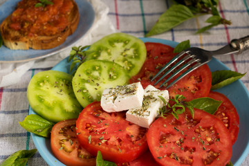 Tomatenscheiben auf einem Teller mit Schafskäse und Bruschetta 