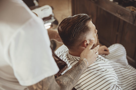 Barber lubricates the client's beard with oil.  Photo in vintage style