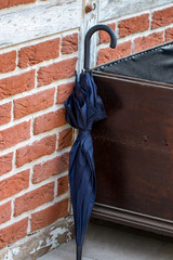 Black umbrella on brick wall background close up