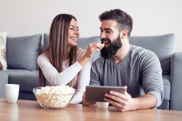 Happy loving couple with coffee cups and tablet