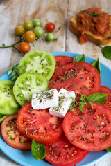 Teller mit roten und grünen Tomatenscheiben und Feta