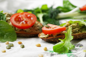 Fototapeta na wymiar Vegan and vegetarian sandwiches with tofu paste, greens, tomatoes, pine nuts, pumpkin seeds and lettuce.
