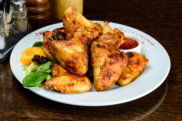 Appetizing spicy baked chicken wings with sweet chili sauce on t