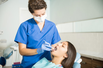 Dentist Examining Girl With Dental Mirror In Clinic
