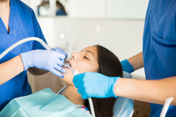 Medical Team Examining Girl With Dental Equipment At Clinic