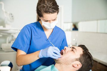 Dentist Examining Man With Dental Carver At Clinic