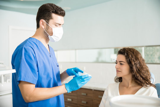 Dentist Explaining Dental Mold To Woman In Clinic