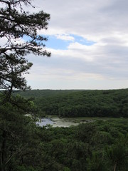 Fototapeta premium View over the edge of a cliff on a mountain on Lantern Hill trail in Connecticut, with a pond below in the distance 