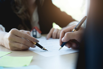 Client signing a real estate contract in real estate agency with house model