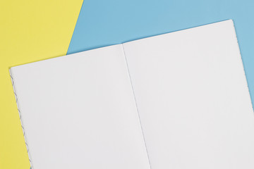 Open notebook and colorful notebooks on blue and yellow background