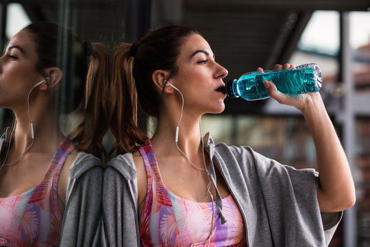 Sportive woman drinking water on street