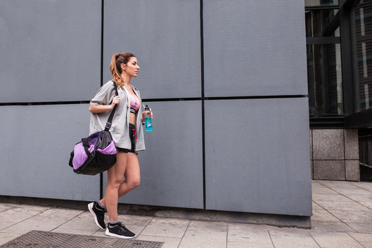 Sportswoman with bag walking on street