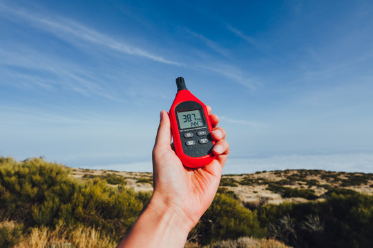 portable thermometer in hand measuring outdoor air temperature and humidity