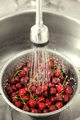 Cherry washing in the colander under water jet.