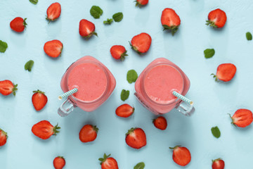 Two mason jars with strawberry on blue background.