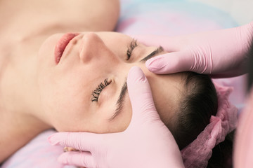 Young woman lying with closed eyes and having head massage in spa